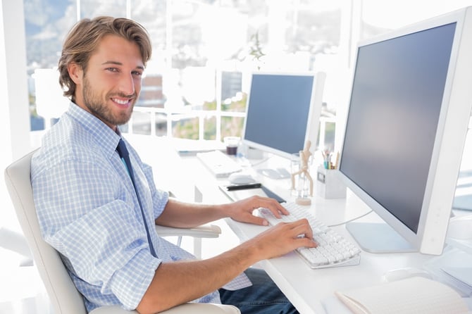 Smiling designer working at his desk in modern office.jpeg