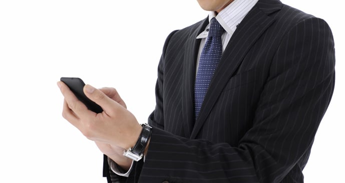 スーツを着た男性がスマートフォンを操作する様子
